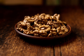 Peeled walnuts on a plate. Dark wooden background. Vegetarian, healthy food.