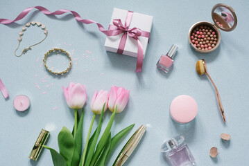 Obraz na płótnie Canvas the composition of cosmetics and beauty products cream, pink tulips, a gift with a pink bow on a mint background with confetti.Flat lay
