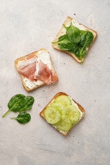 White toasts with cream cheese, ham, cucumbers and spinach