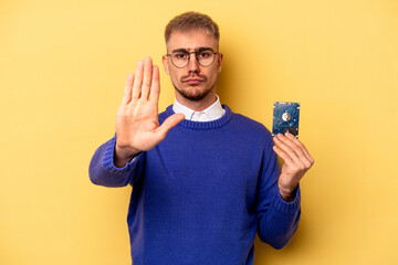 Young computer man isolated on yellow background standing with outstretched hand showing stop sign, preventing you.