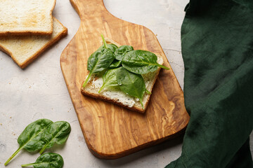 White toasts with cream cheese and spinach on a wooden board