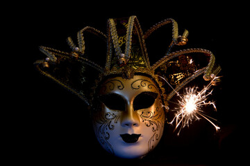 Venetian carnaval mask on black background with sparks.