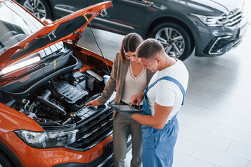 Showing results of work. Man repairing woman's automobile indoors. Professional service