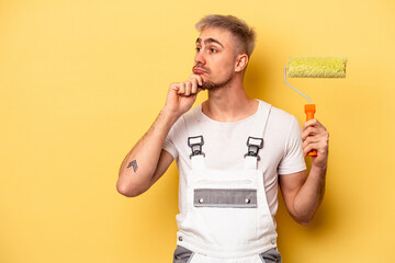 Young painter man isolated on yellow background looking sideways with doubtful and skeptical...