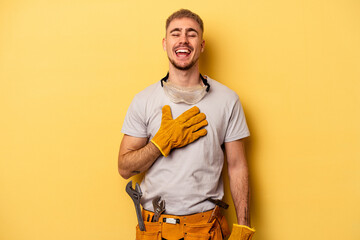 Young electrician caucasian man isolated on yellow background laughs out loudly keeping hand on...