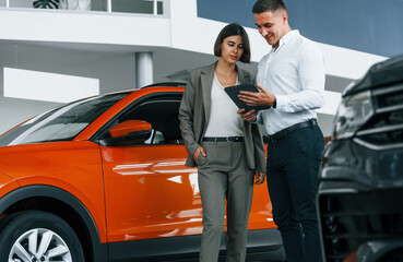 Modern vehicles. Man in formal wear helping customer with choice of the automobile