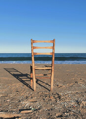 View of a solitary chair on the shore of the beach representing stillness, relaxation and reflection.