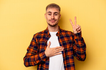 Young caucasian man isolated on yellow background taking an oath, putting hand on chest.