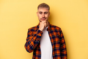 Young caucasian man isolated on yellow background thinking and looking up, being reflective, contemplating, having a fantasy.