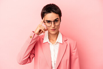 Young business woman wearing a pink blazer isolated on pink background pointing temple with finger,...