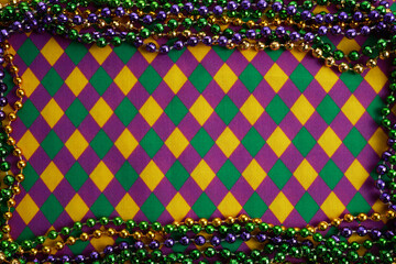 Frame of colorful Mardi Gras Beads on diamond shaped background