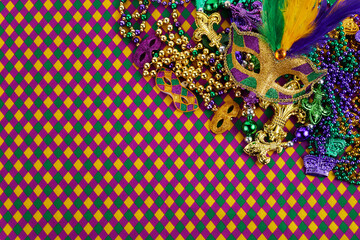 Frame of Mardi Gras Mask and colorful Mardi Gras Beads on diamond shaped background © vetre