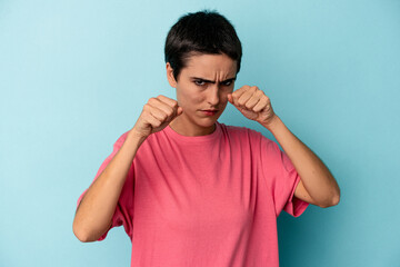 Young caucasian woman isolated on blue background throwing a punch, anger, fighting due to an argument, boxing.