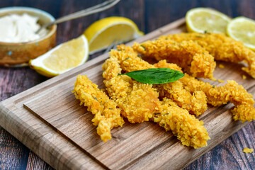 
 Crispy  deep fried   chicken strips and wedges potato. Breaded  with cornflakes chicken  breast fillets  with chilly peppers and fresh   basil on wooden rustic background