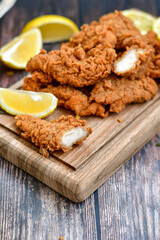 
 Crispy  deep fried   chicken strips and wedges potato. Breaded  with cornflakes chicken  breast fillets  with chilly peppers and fresh   basil on wooden rustic background