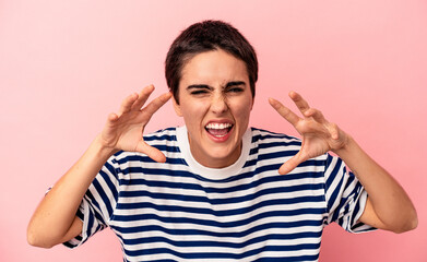 Young caucasian woman isolated on blue background showing claws imitating a cat, aggressive gesture.