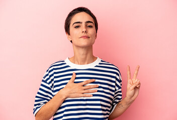 Young caucasian woman isolated on blue background taking an oath, putting hand on chest.