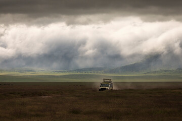 Fototapeta na wymiar Safari car on a road in Ngorongoro National Park, Tanzania with beautiful clouds in background. Wild nature of Africa.