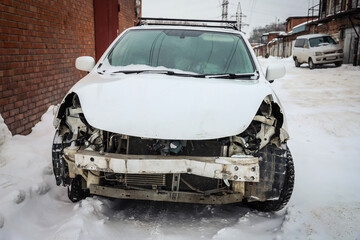 Disassembled damaged car after an accident on the street. Deformed hood. Without headlights and...