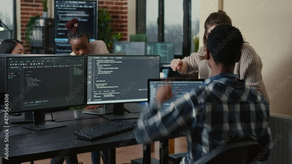 Poster software developer looking at running code on multiple screens takes off glasses and doing high five