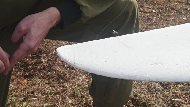 Repairing of broken drone wing. Man wipes glue remainings from a wing.