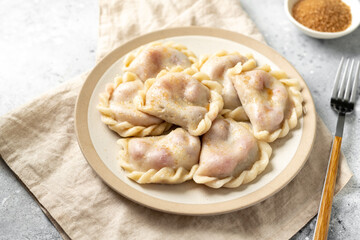 Dumplings with cherries on a plate on the kitchen table closeup