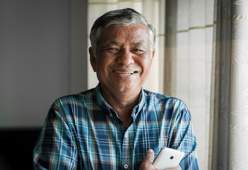 Close up, portrait of older man smiling and looking at the camera in the room at home.