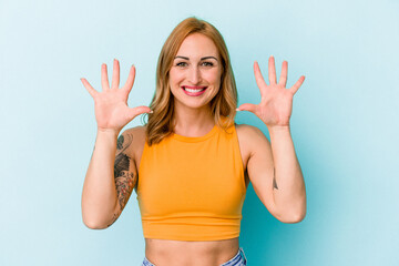 Young caucasian woman isolated on blue background showing number ten with hands.