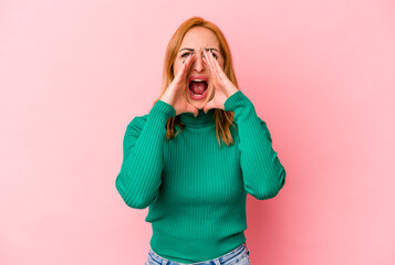 Young caucasian woman isolated on pink background shouting excited to front.