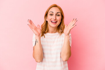 Young caucasian woman isolated on pink background laughs out loudly keeping hand on chest.