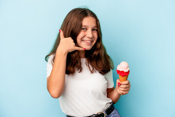 Little caucasian girl eating an ice cream isolated on blue background showing a mobile phone call gesture with fingers.