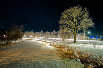 winter scene in the evening by the river with iluminated trees