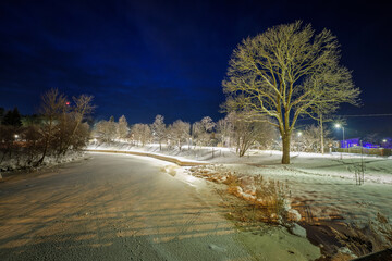 winter scene in the evening by the river with iluminated trees