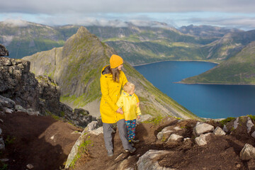 Fototapeta premium Happy family, standing on a rock and looking over Segla mountain on Senja island, North Norway. Amazing beautiful landscape and splendid nature