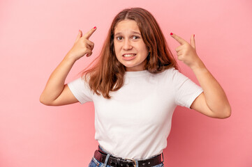 Little caucasian girl isolated on pink background showing a disappointment gesture with forefinger.