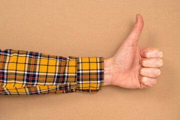 Hand with thumb upwards on a brown paper background