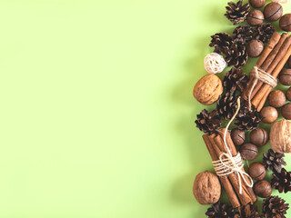 Christmas or New Year natural composition of nuts and cones in the form on the green background. Beige and green natural design.