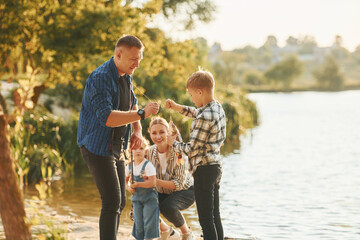 Rural scene. Father and mother with son and daughter on fishing together outdoors at summertime