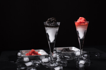 Caviar de esturión negro y caviar de salmón rojo servido en copa de cóctel helada sobre fondo negro	