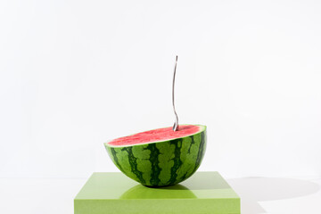 Media sandía con una cuchara en el interior sobre fondo blanco