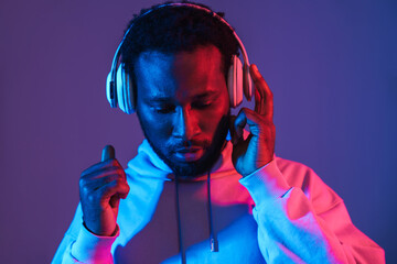 Young black man in hoodie listening music with headphones