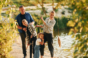 Father and mother with son and daughter on fishing together outdoors at summertime