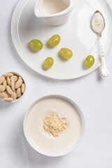 Crema de almendras, sopa fría española. Ajo blanco de Málaga con almendras y uvas en un recipiente blanco sobre una mesa blanca. Vista superior