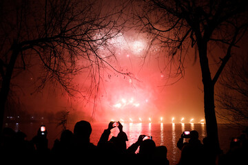 People watch fireworks and a laser show over the lake during New Years celebrations in the Alexandru Ioan Cuza park in Bucharest.