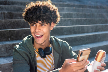 Close up happy guy eating and holding mobile phone