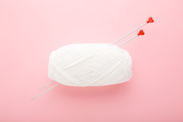 White wool clew and metal needles with red heart shapes for knitting clothes or other things. Light...