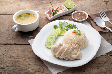 Sliced Hainan-style chicken with marinated rice served with chilli sauce and cucumber in white...