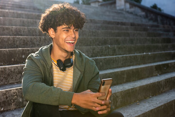 Fototapeta premium laughing young man sitting on steps with cellphone