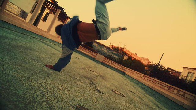 Activel Young Latin Man in Stylish Clothes Actively Breakdancing, Spinning on Hands on the Street of an Old Town in a City. Scene Shot in an Urban Environment in Ancient Cultural Tourist Location.