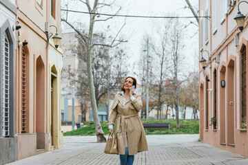 Fototapeta premium Woman talking on the phone while walking down the street.